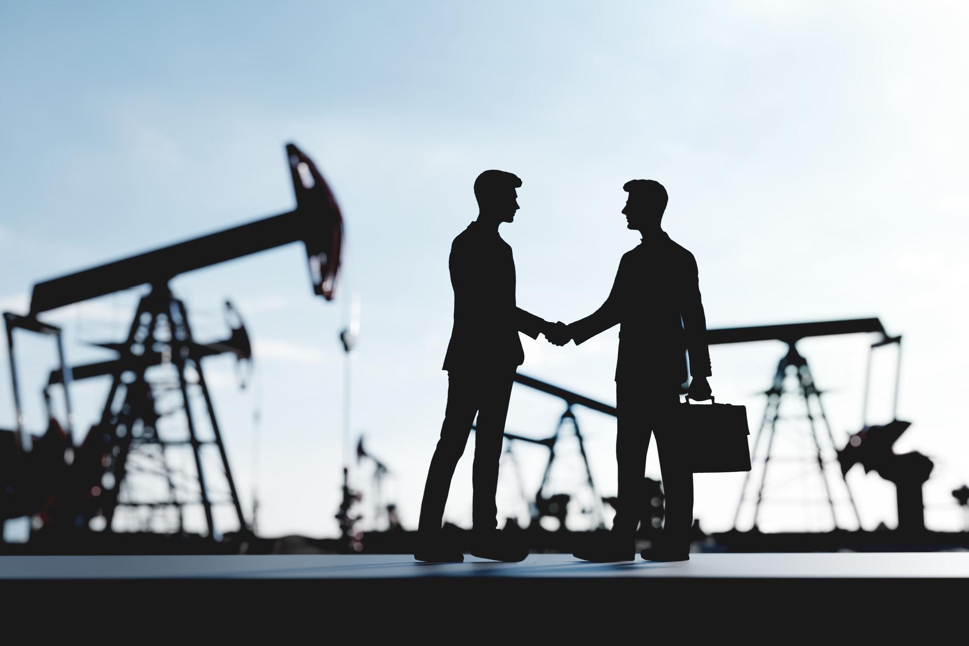 Two businessmen, investors making a deal, handshake in oil pump station. Oil industry